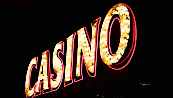 Brightly illuminated letters spell out 'CASINO' with glowing yellow bulbs and red outlines against a dark background.
